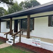A white house with a porch and stairs is for sale.
