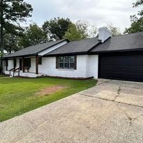 A white house with a black garage door and a black roof.