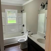 A bathroom with a toilet , sink , tub and mirror.