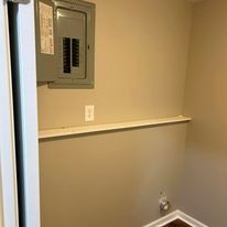 A laundry room with a electrical box on the wall.