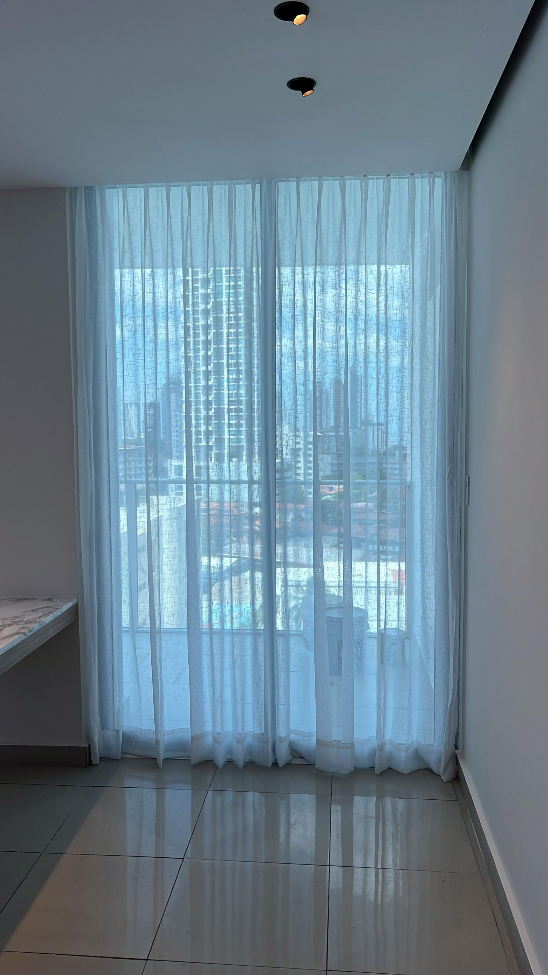 Cortinas blancas translúcidas cubren una ventana en un interior moderno. L