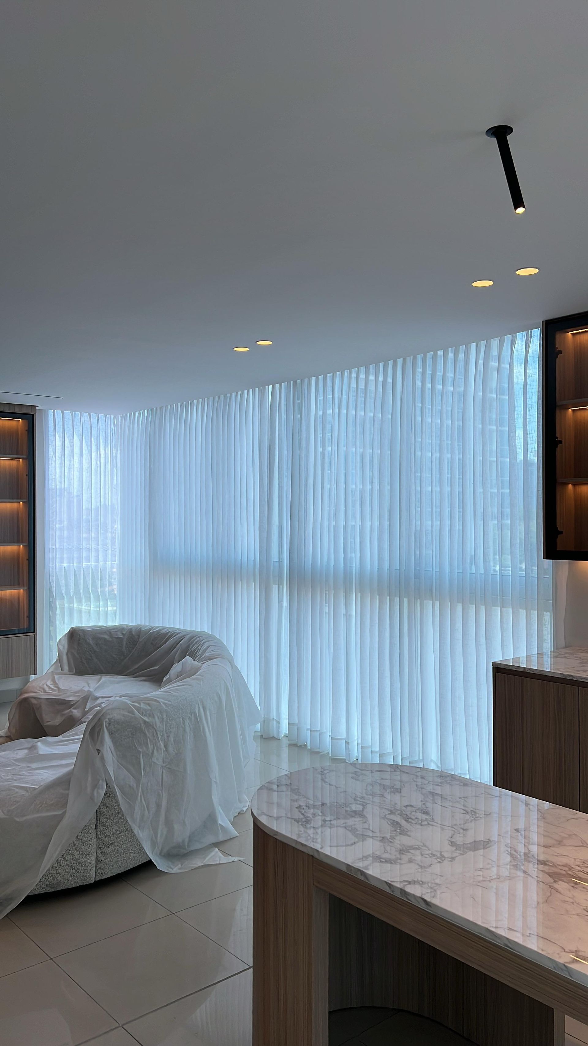Sala de estar con cortinas blancas transparentes, un sofá tapizado y una encimera de mármol.