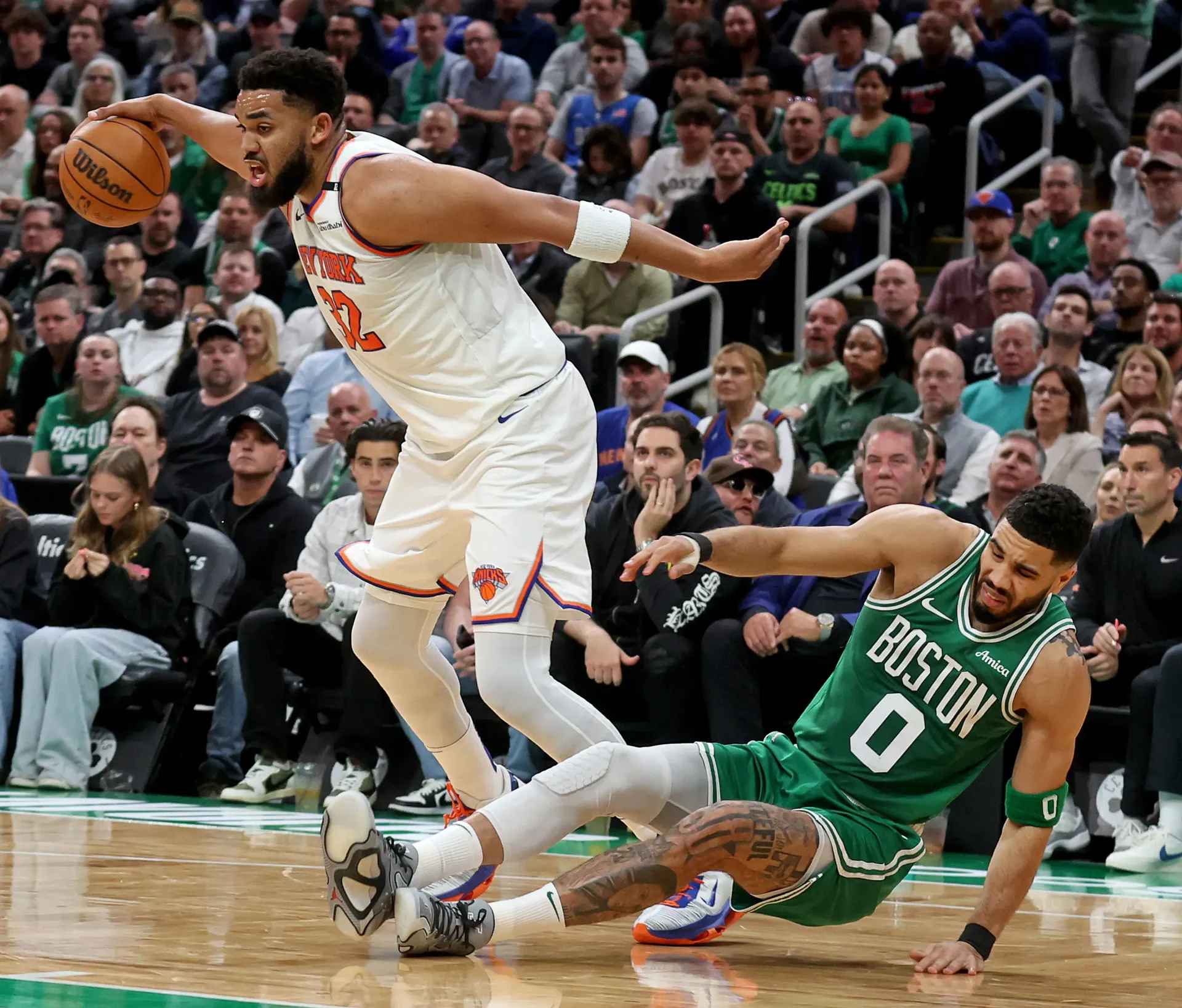 Two basketball players are playing a game of basketball on a court.
