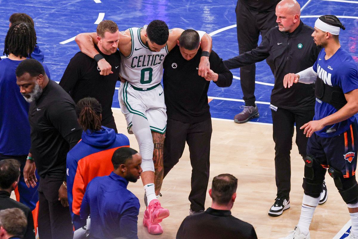 A basketball player is being helped off the court during a game.