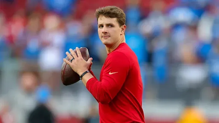 A man in a red shirt is throwing a football on a field.