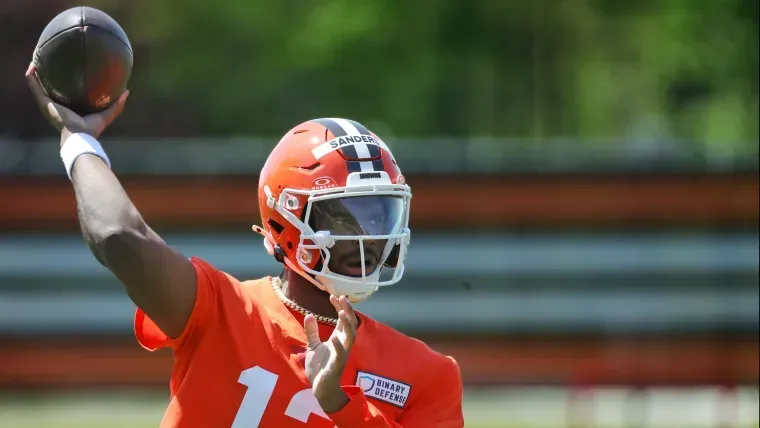 A football player in an orange uniform is throwing a football.