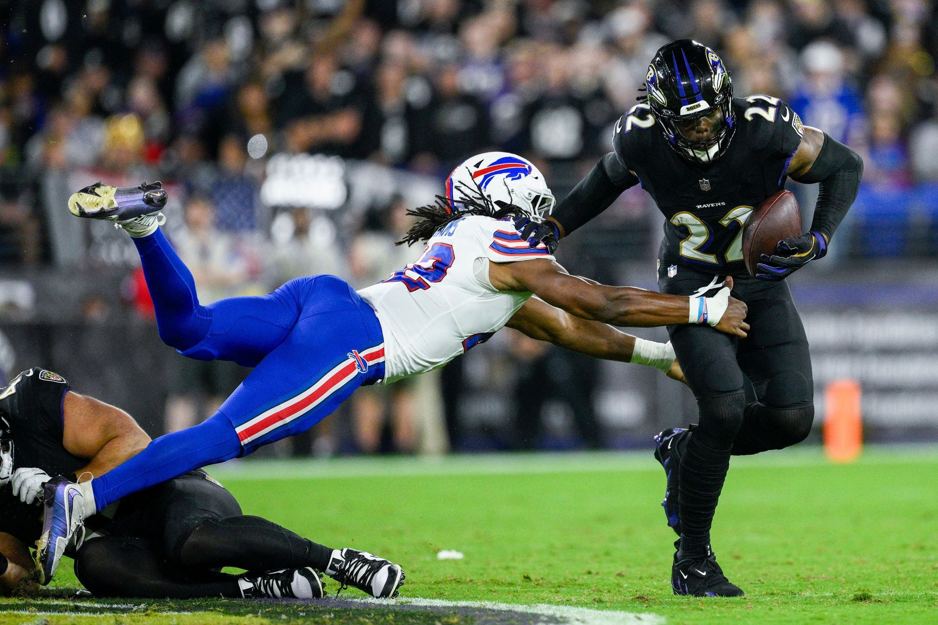 a man in white diving towards a man in black holding a ball