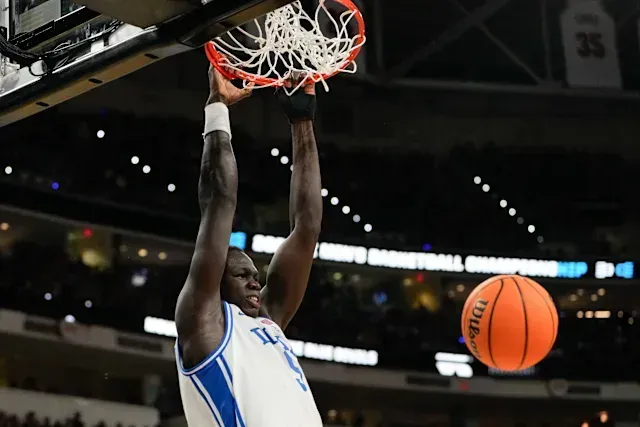 A basketball player is dunking a basketball into the net