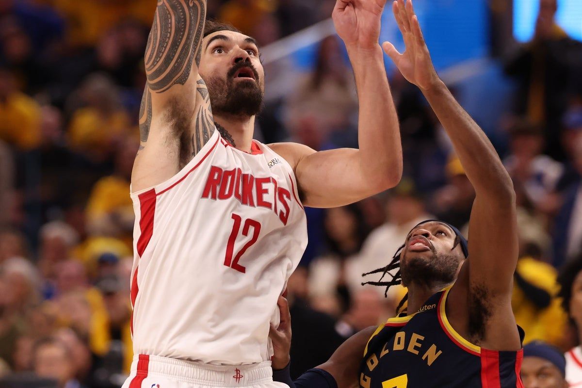 two players jumping to reach the basketball hoop