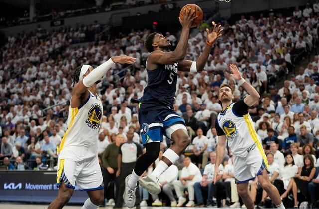 A group of basketball players are playing a game of basketball in front of a crowd.