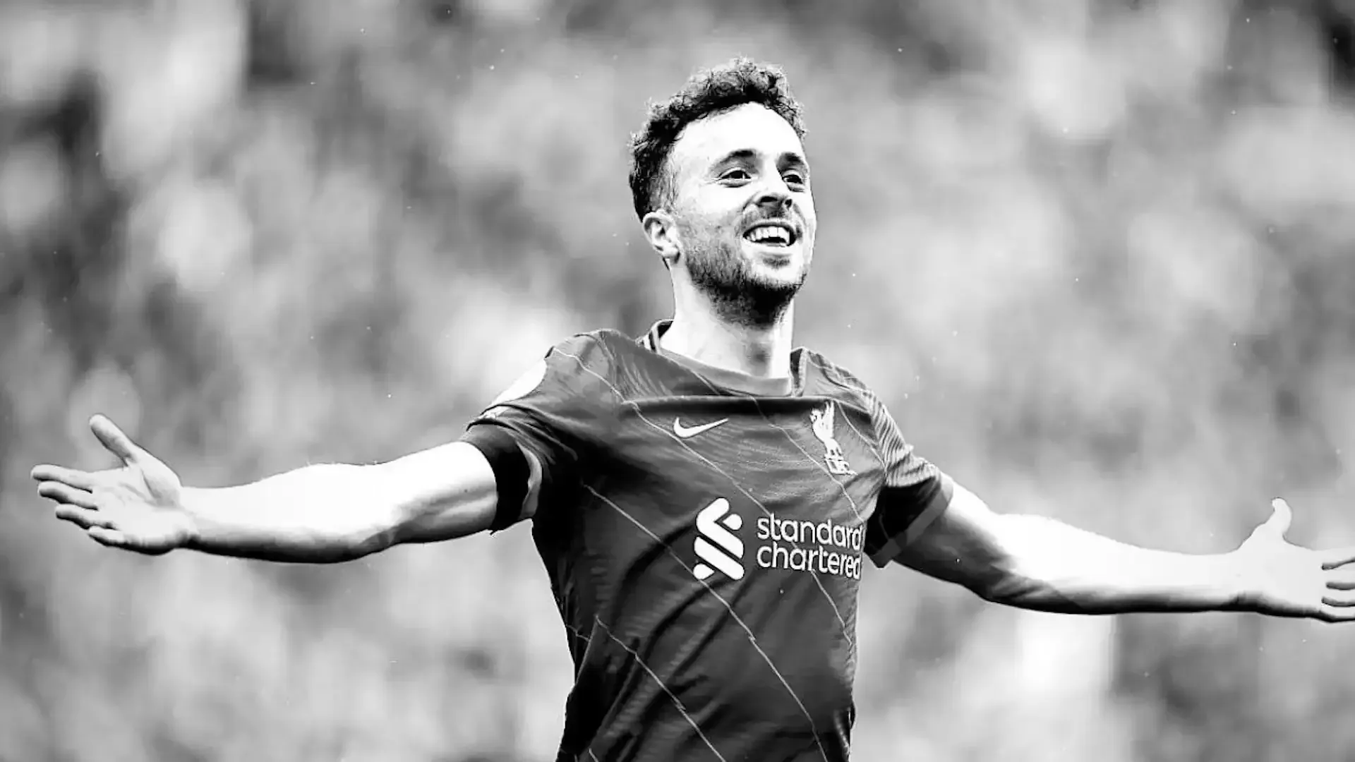 A black and white photo of a soccer player with his arms outstretched.