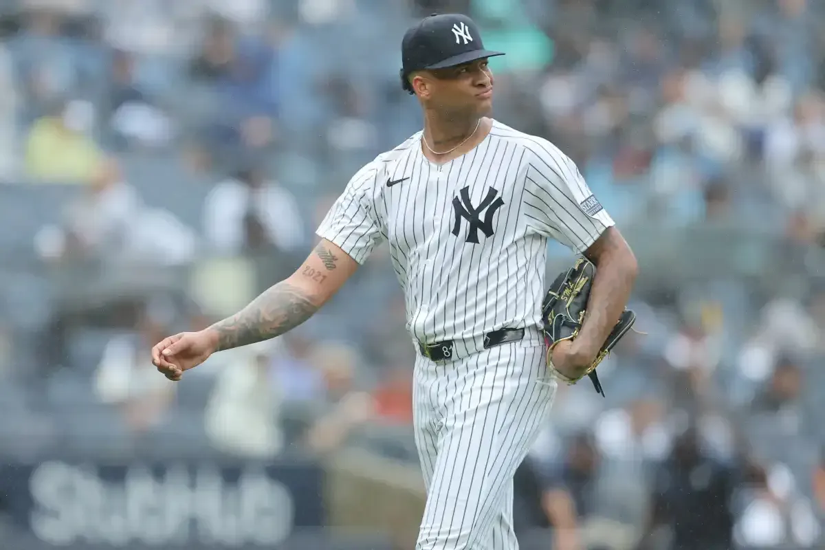 A new york yankees pitcher is walking on the field during a baseball game.