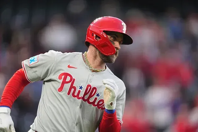 A baseball player wearing a phillies jersey and helmet is running on the field.