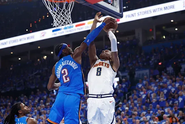 Two basketball players are playing a game of basketball in front of a crowd.