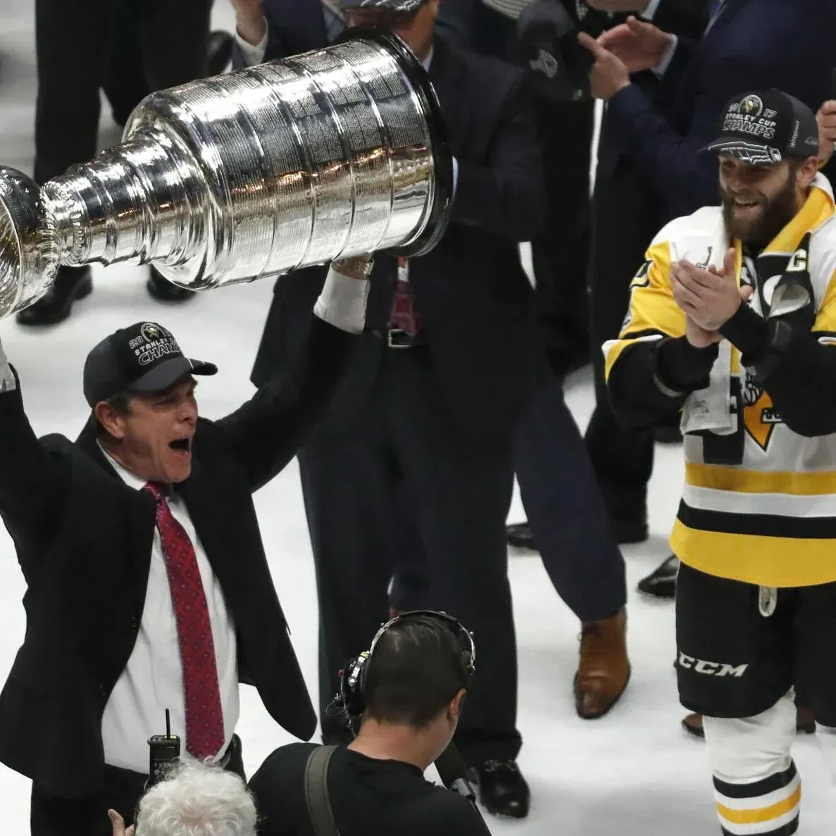 A man in a suit and tie holds up a trophy