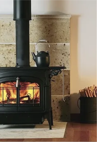 A black wood stove with a kettle on top of it