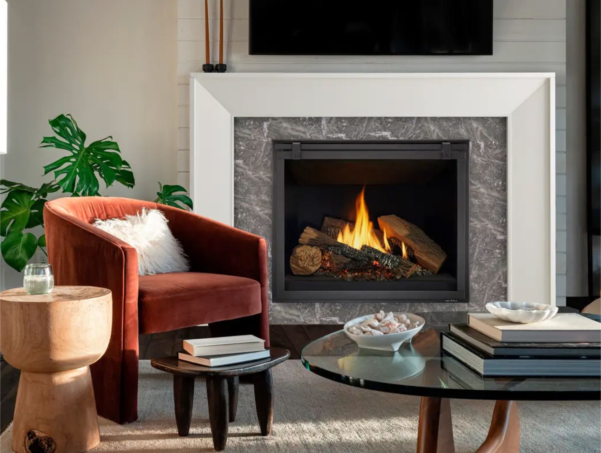 A living room with a fireplace , chair , coffee table and television.