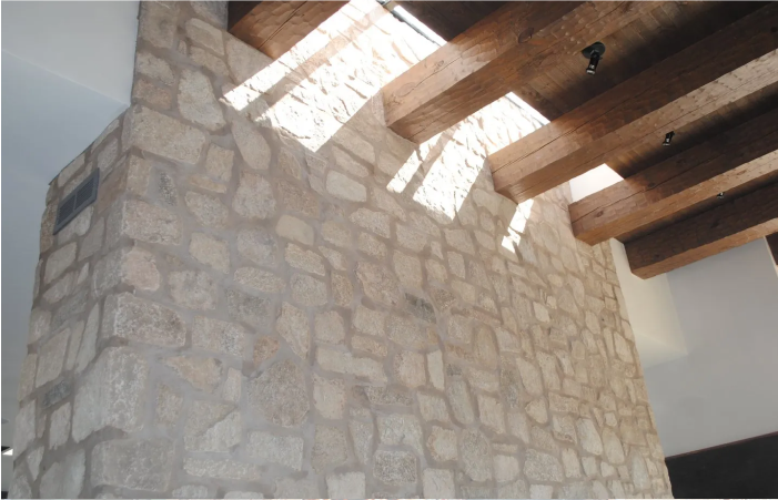 A room with a stone wall and wooden beams