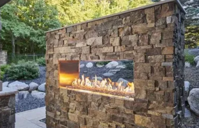 There is a fireplace in the middle of a stone wall.