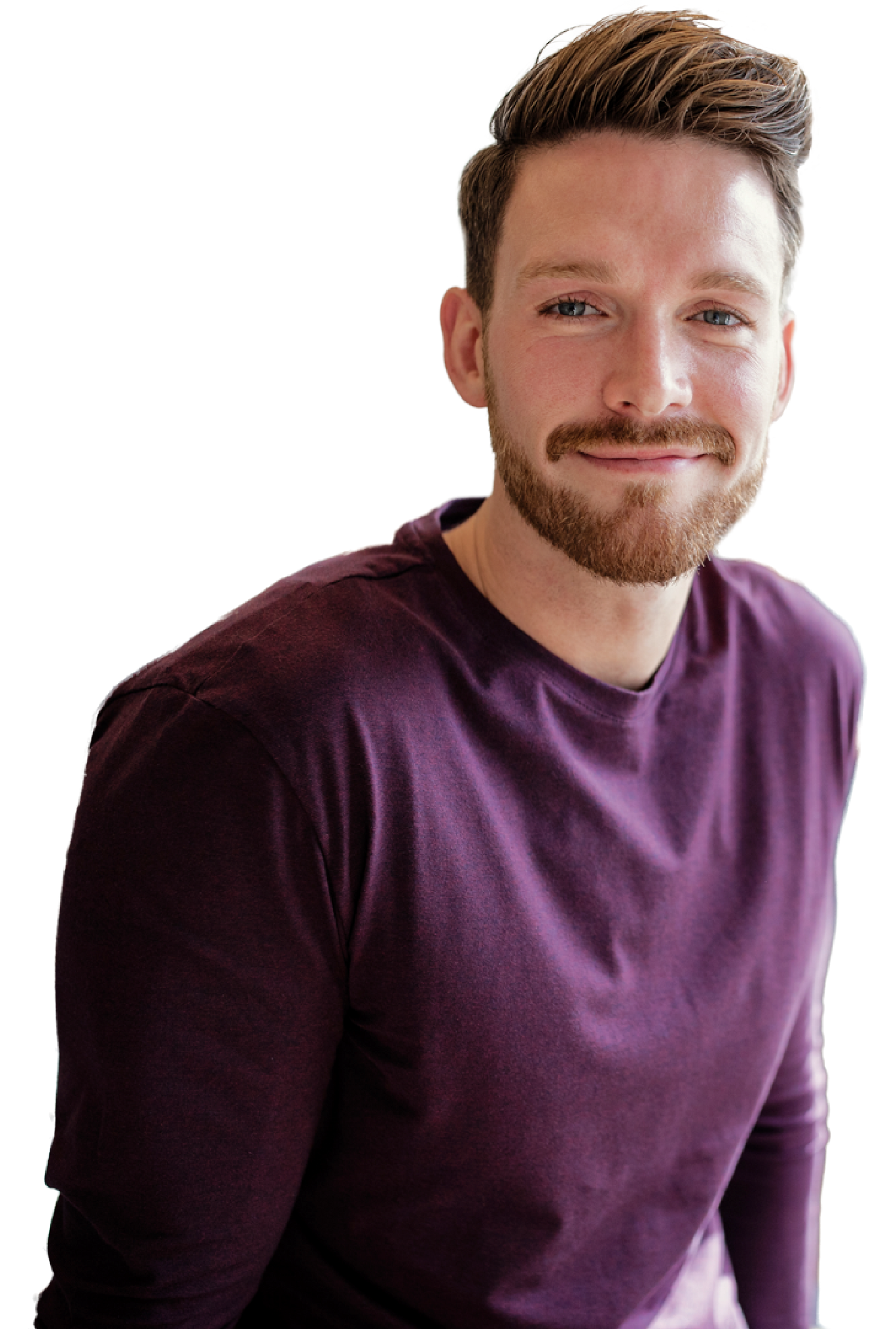 A man with a beard is wearing a purple shirt and smiling.