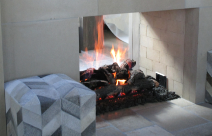 A fireplace with a geometric patterned ottoman in front of it