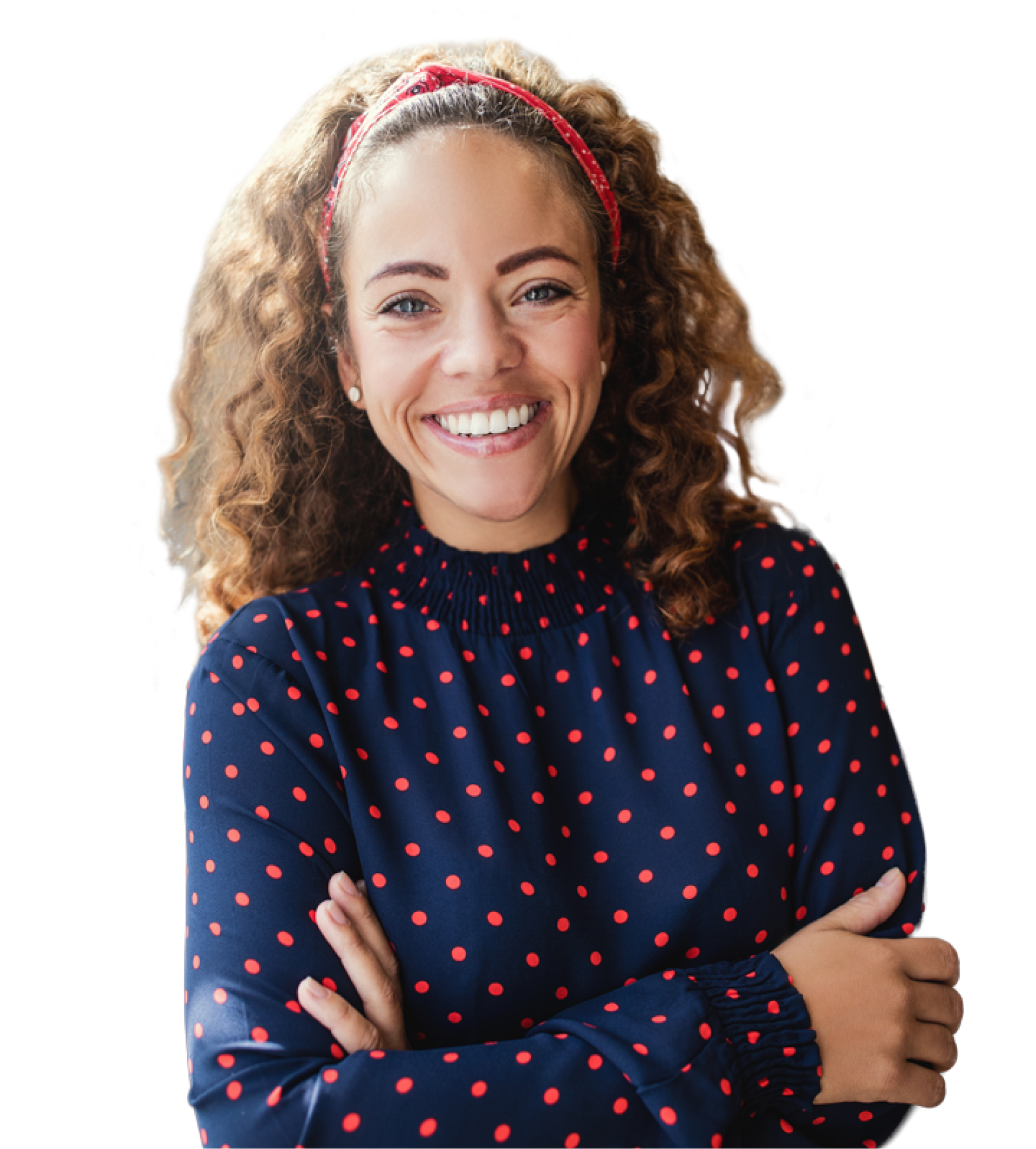 A woman in a blue polka dot shirt is smiling with her arms crossed.