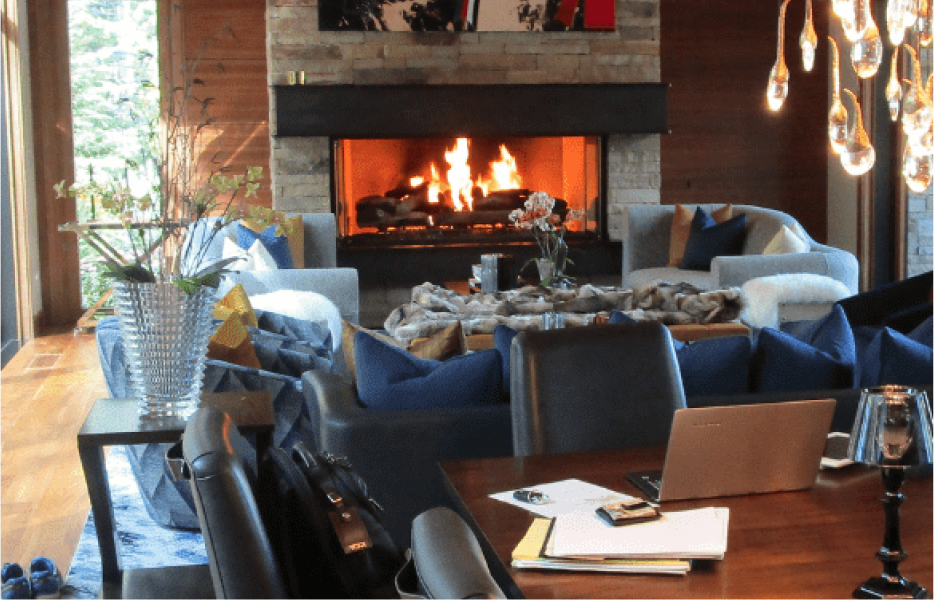 A living room with a fireplace and a laptop on the table