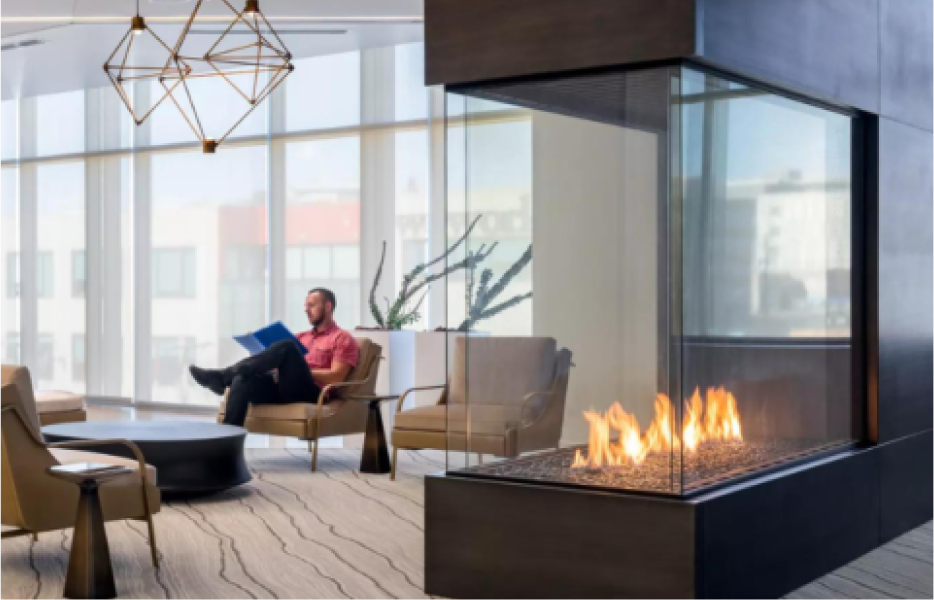 A man is sitting in a chair in front of a fireplace in a living room.