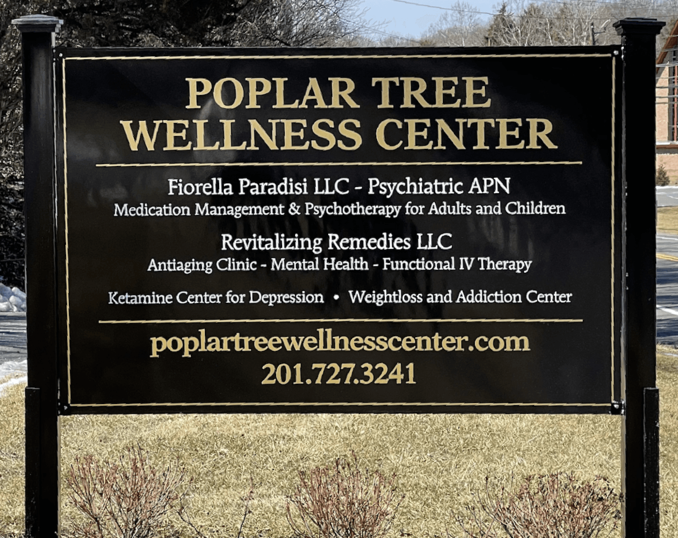 Sign for Poplar Tree Wellness Center with contact information.