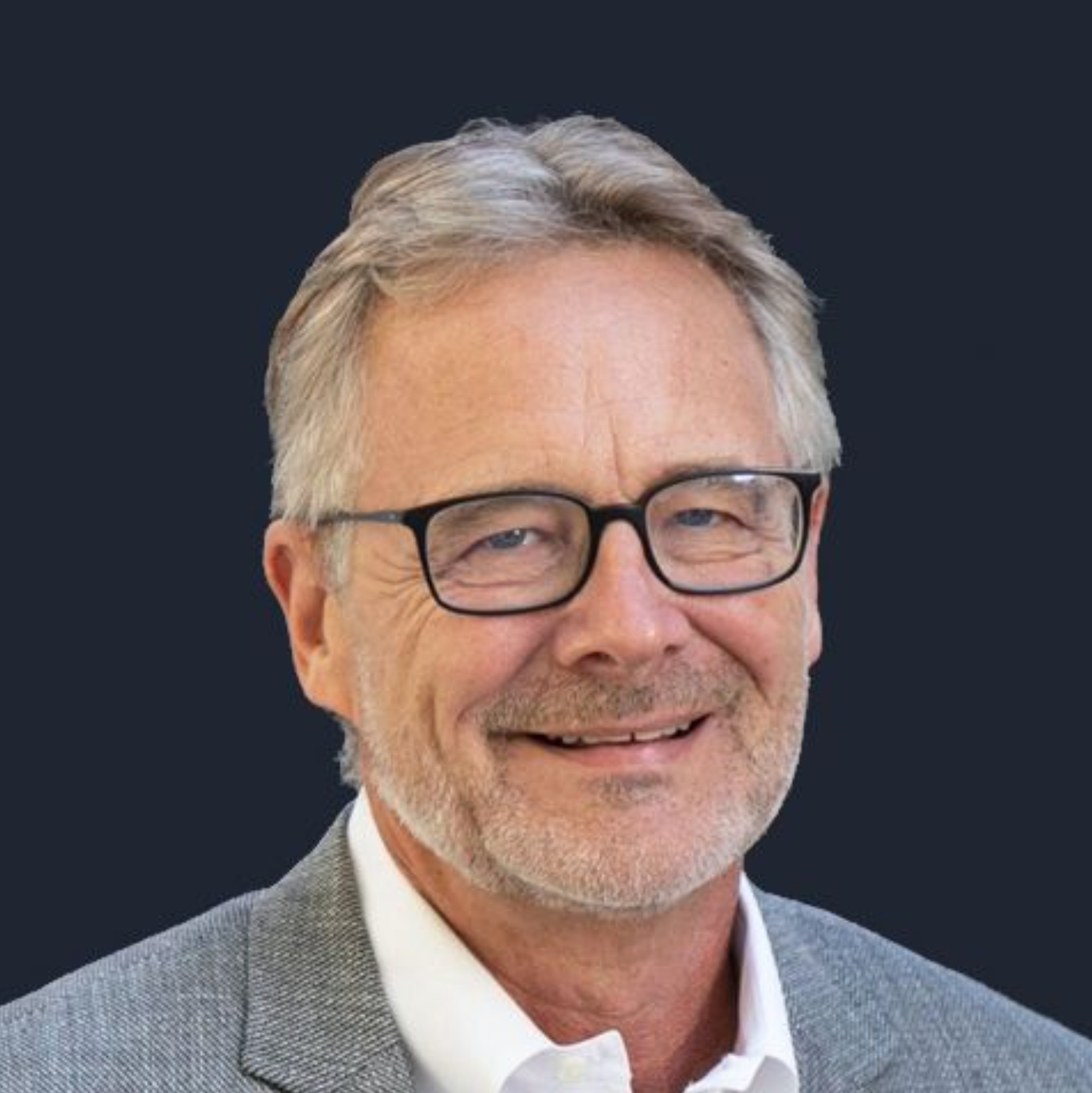 A man with glasses and a beard is smiling for the camera