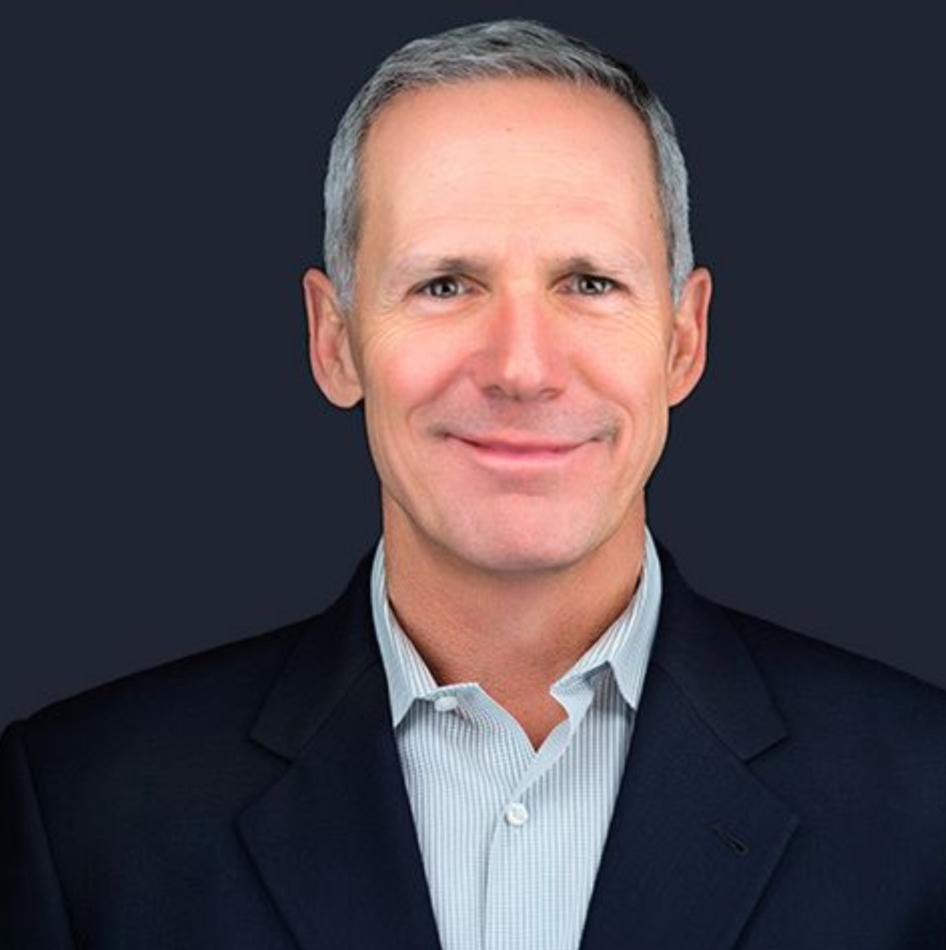 A man in a suit and striped shirt is smiling for the camera.