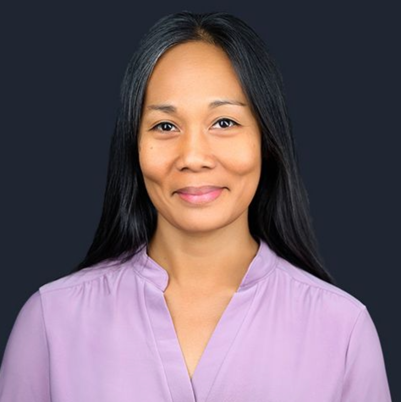 The woman is wearing a purple shirt and smiling for the camera.