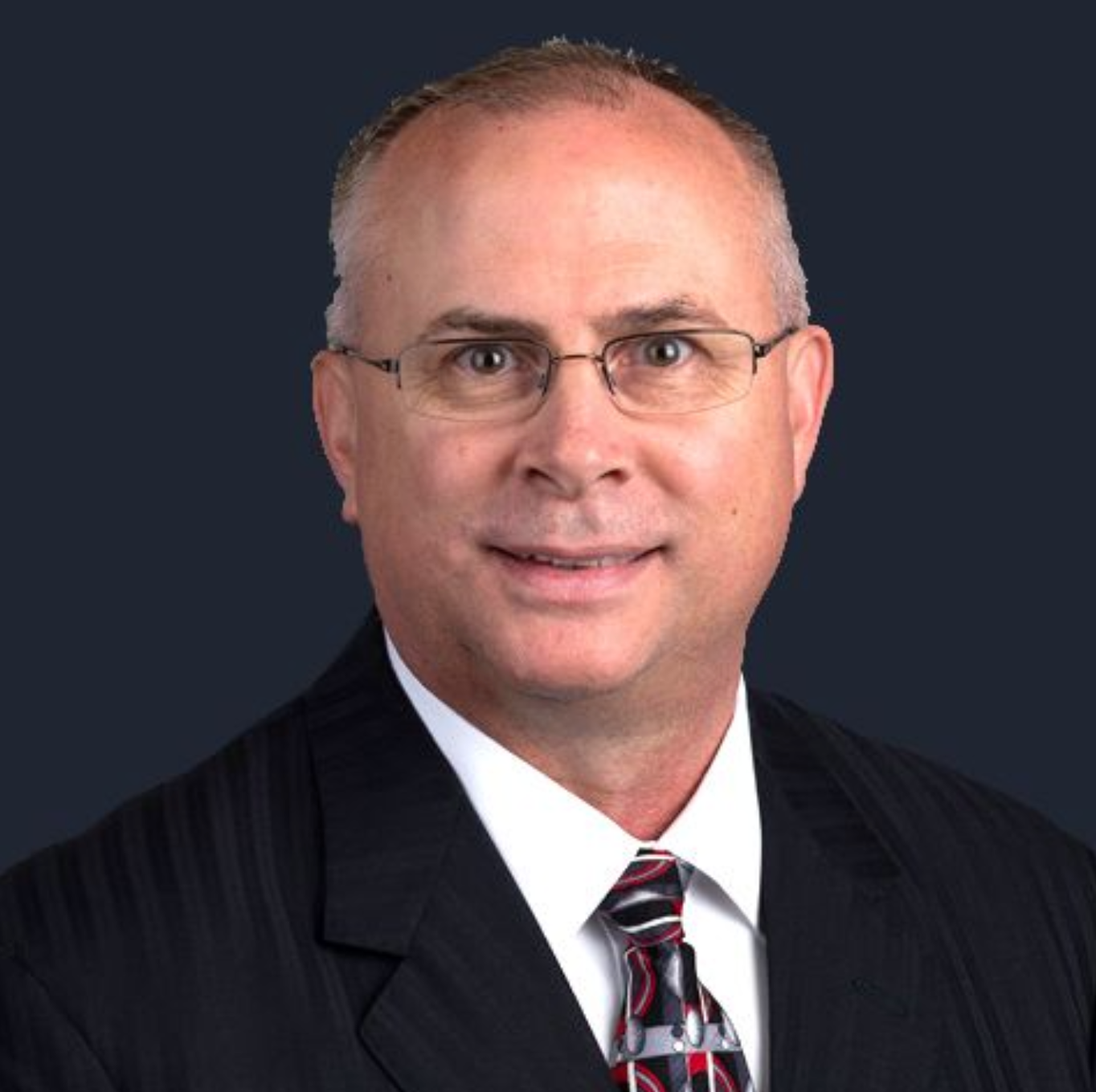 A man in a suit and tie is smiling for the camera