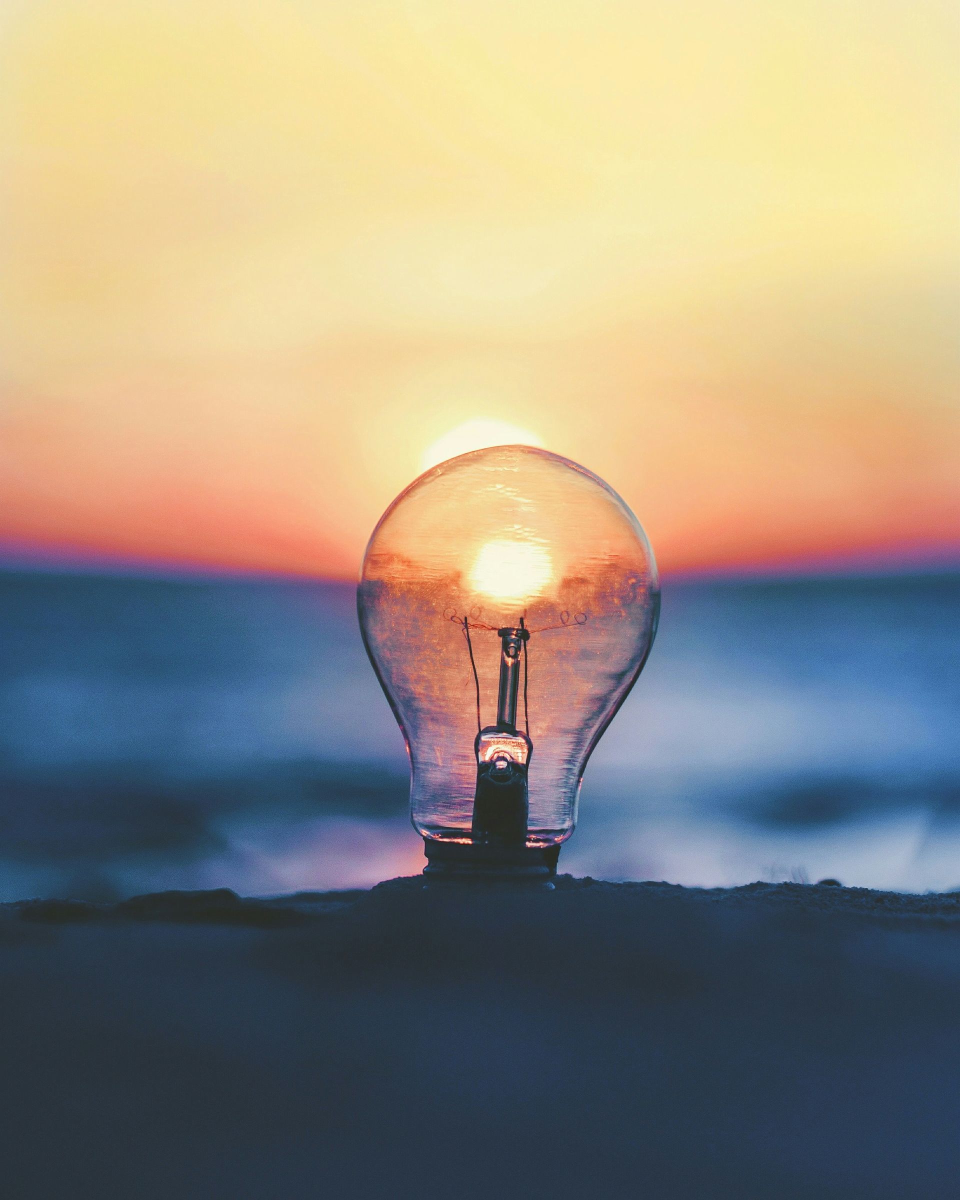 A light bulb is sitting on the beach at sunset.