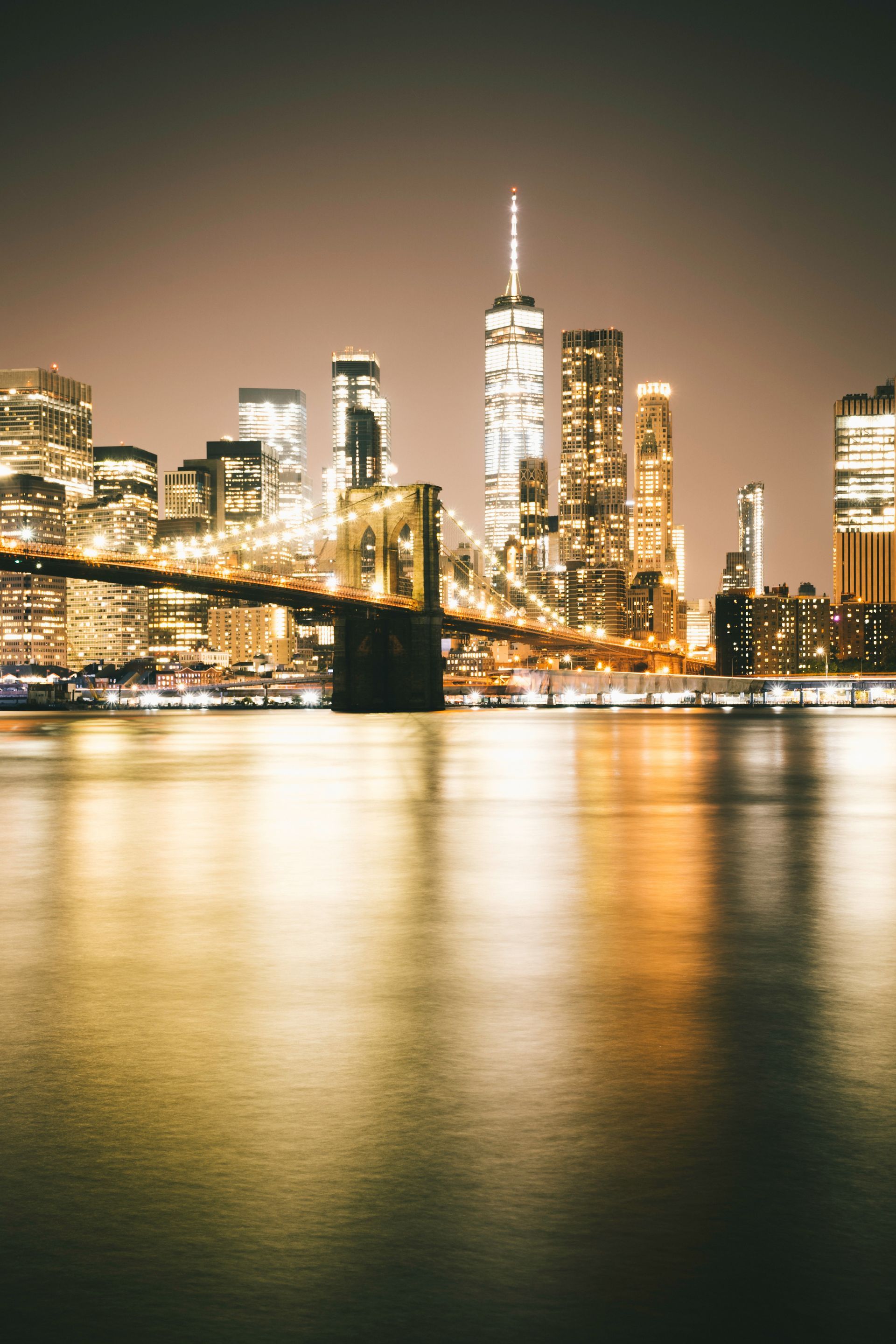 A bridge over a body of water with a city skyline in the background.