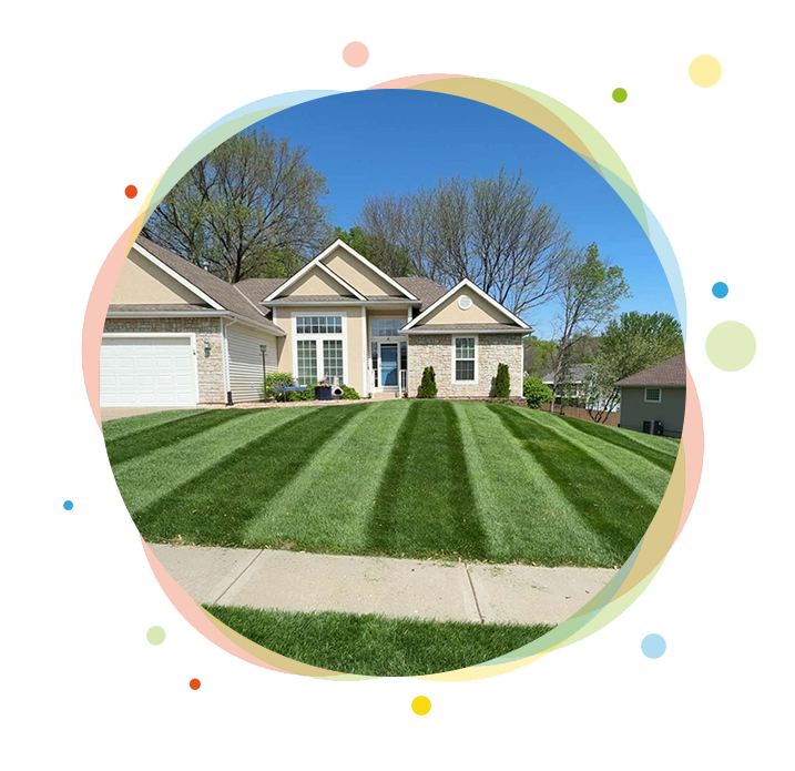 House with striped green lawn under a bright blue sky.