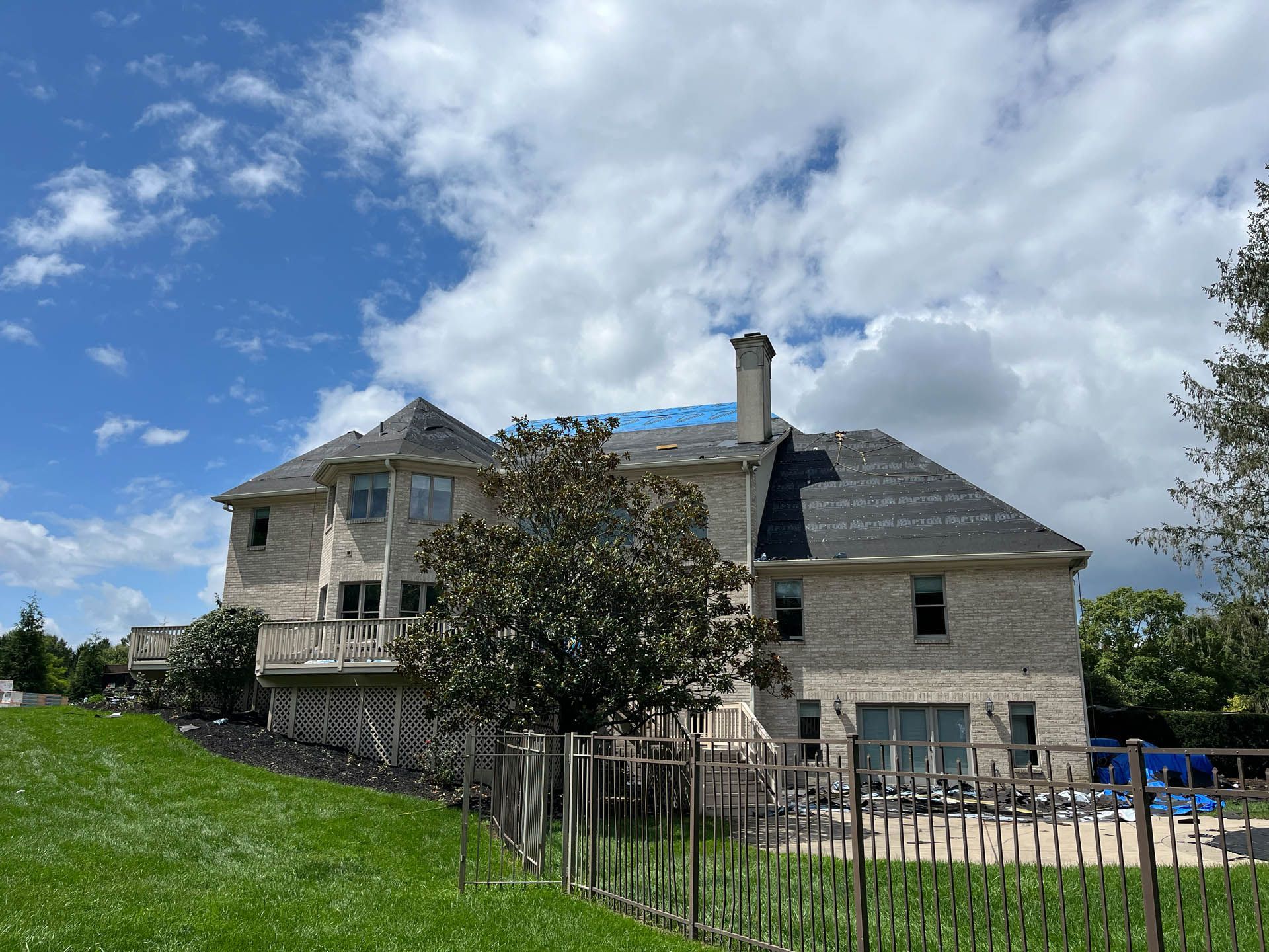 A large house is sitting on top of a lush green hill.