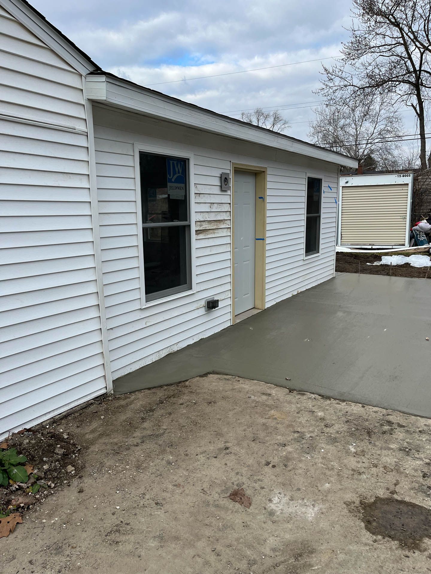 A white house with a concrete walkway leading to it.