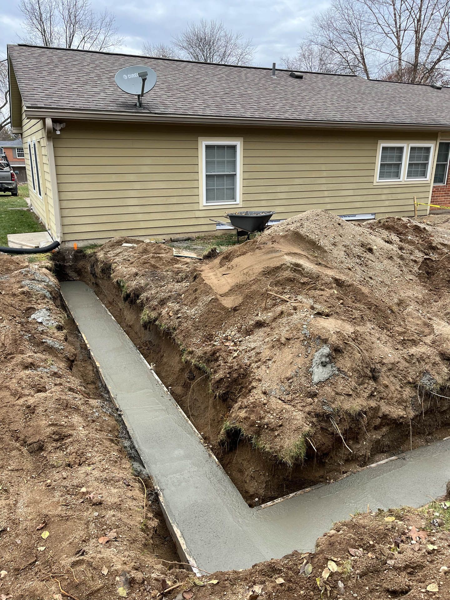 A house is being built with a large pile of dirt in front of it.