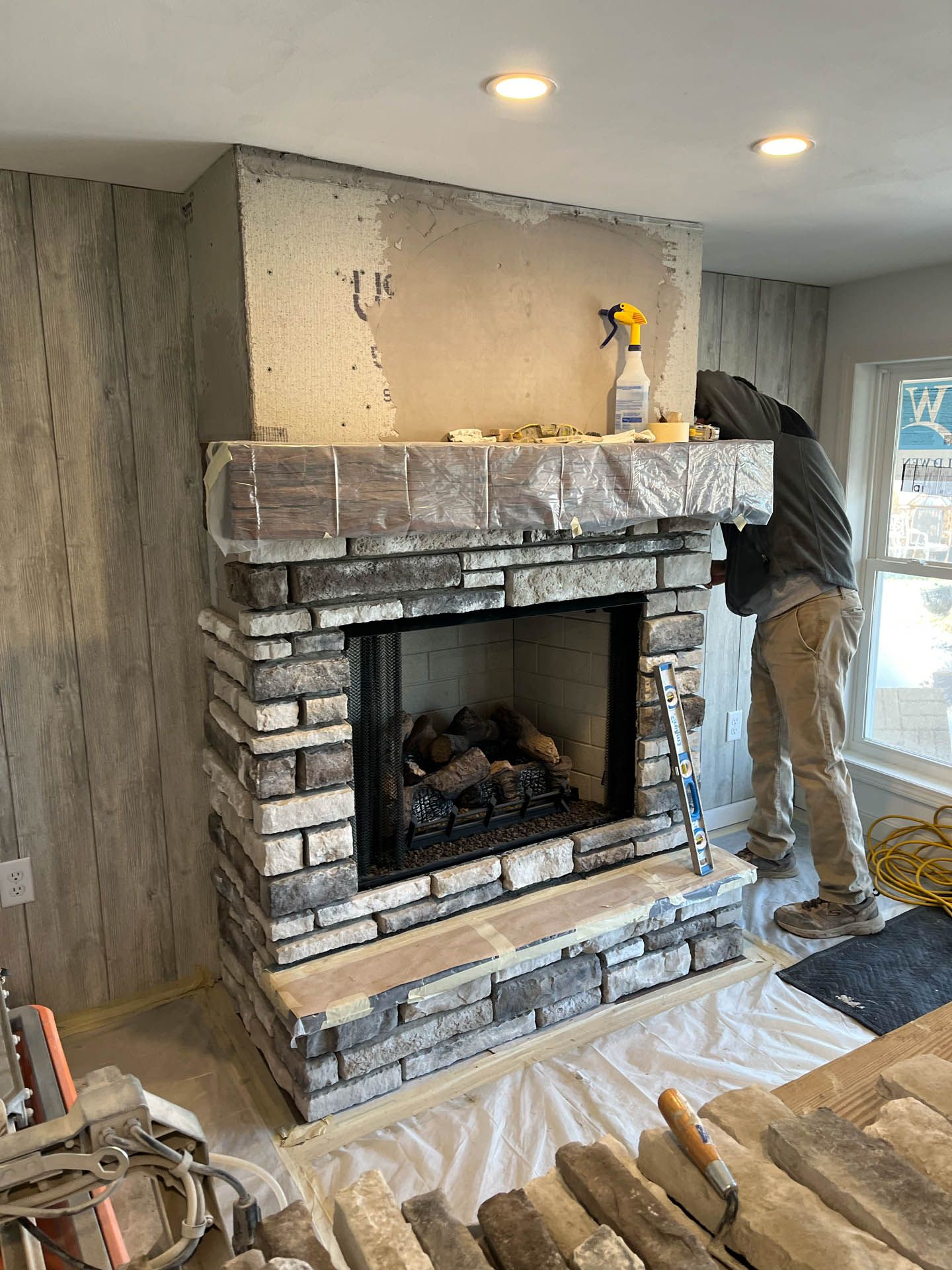 A man is working on a fireplace in a living room.