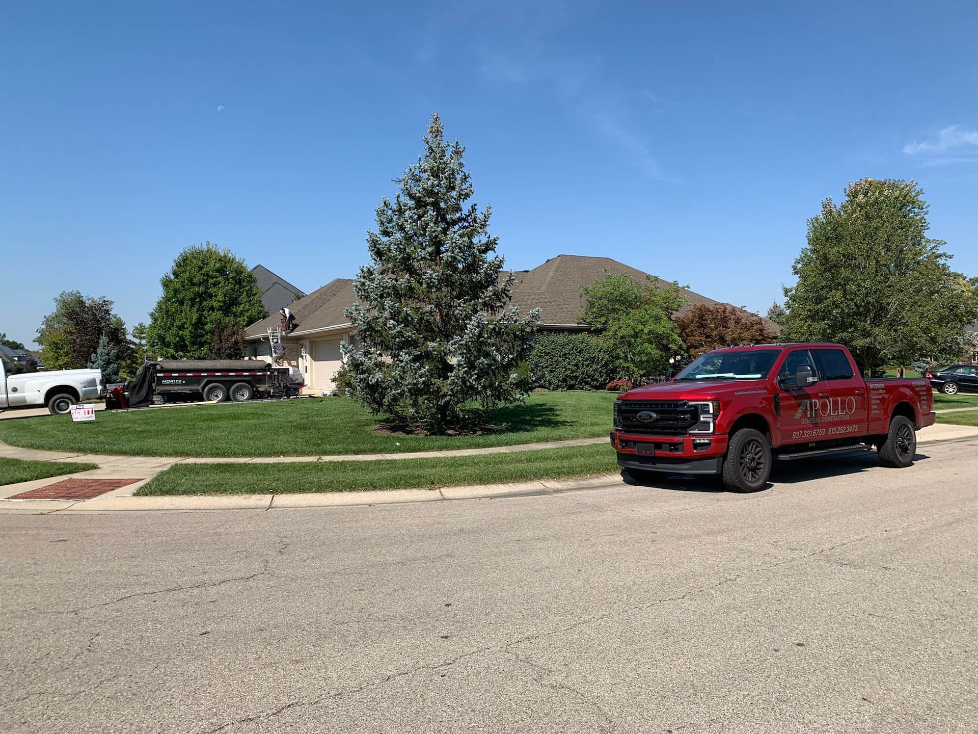 A red truck is parked on the side of the road in front of a house.