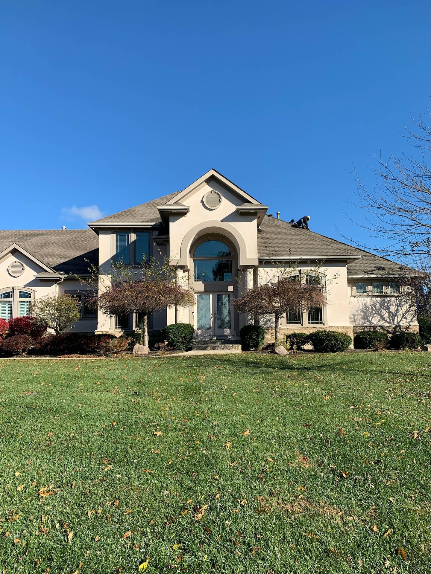 A large house is sitting on top of a lush green field.
