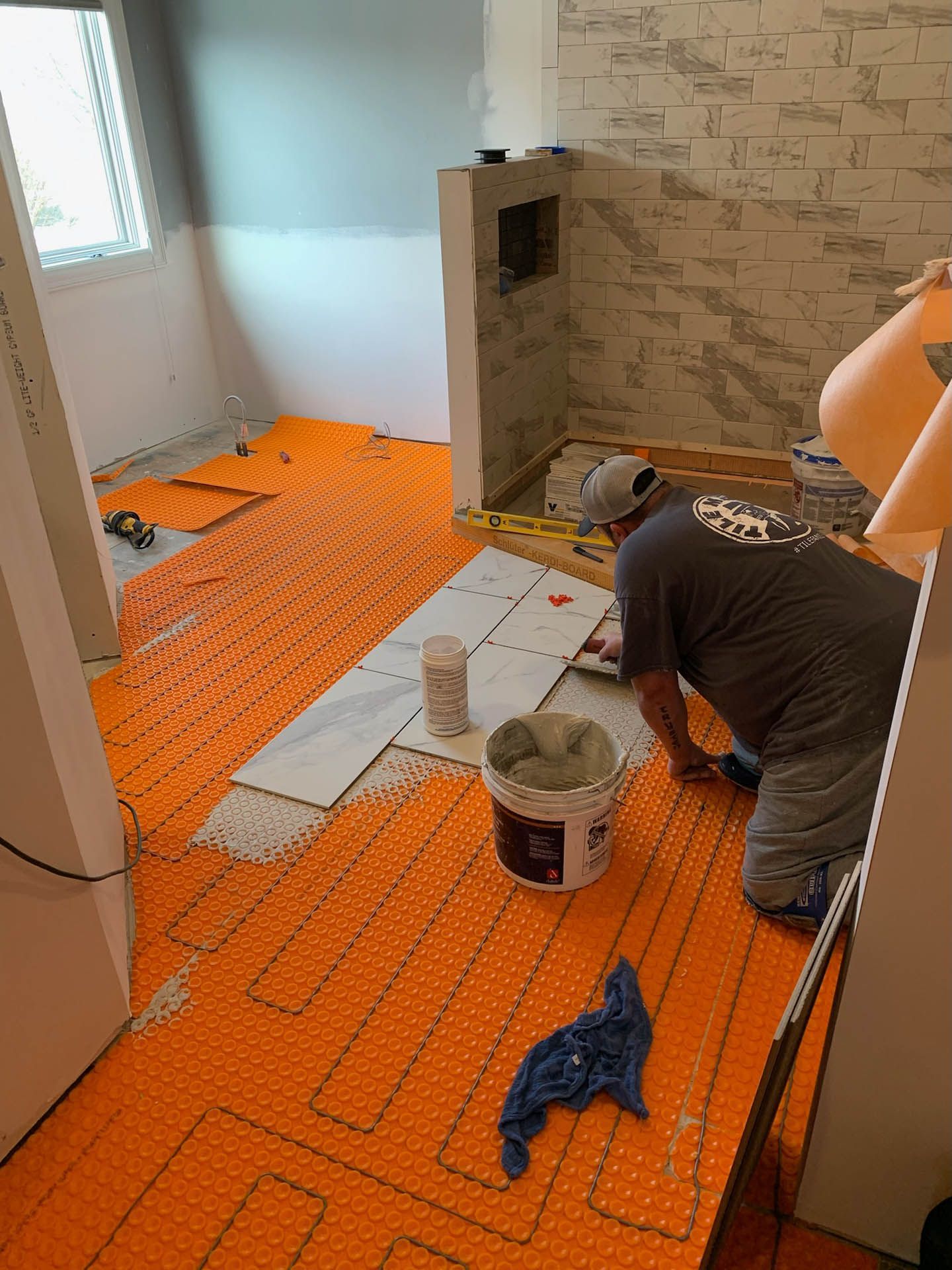 A man is kneeling on a tile floor in a room.