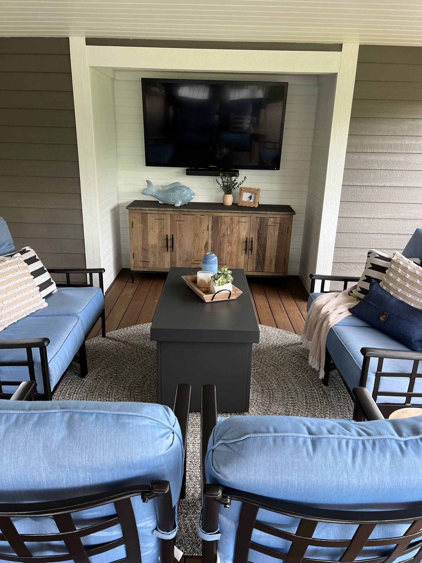 A living room with blue furniture and a flat screen tv on the wall.