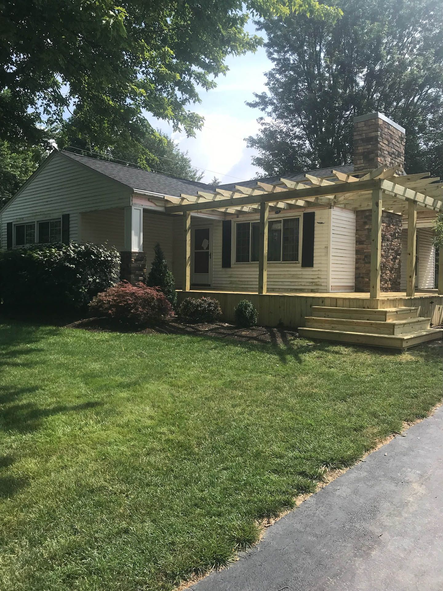 A white house with a wooden porch and a stone chimney.