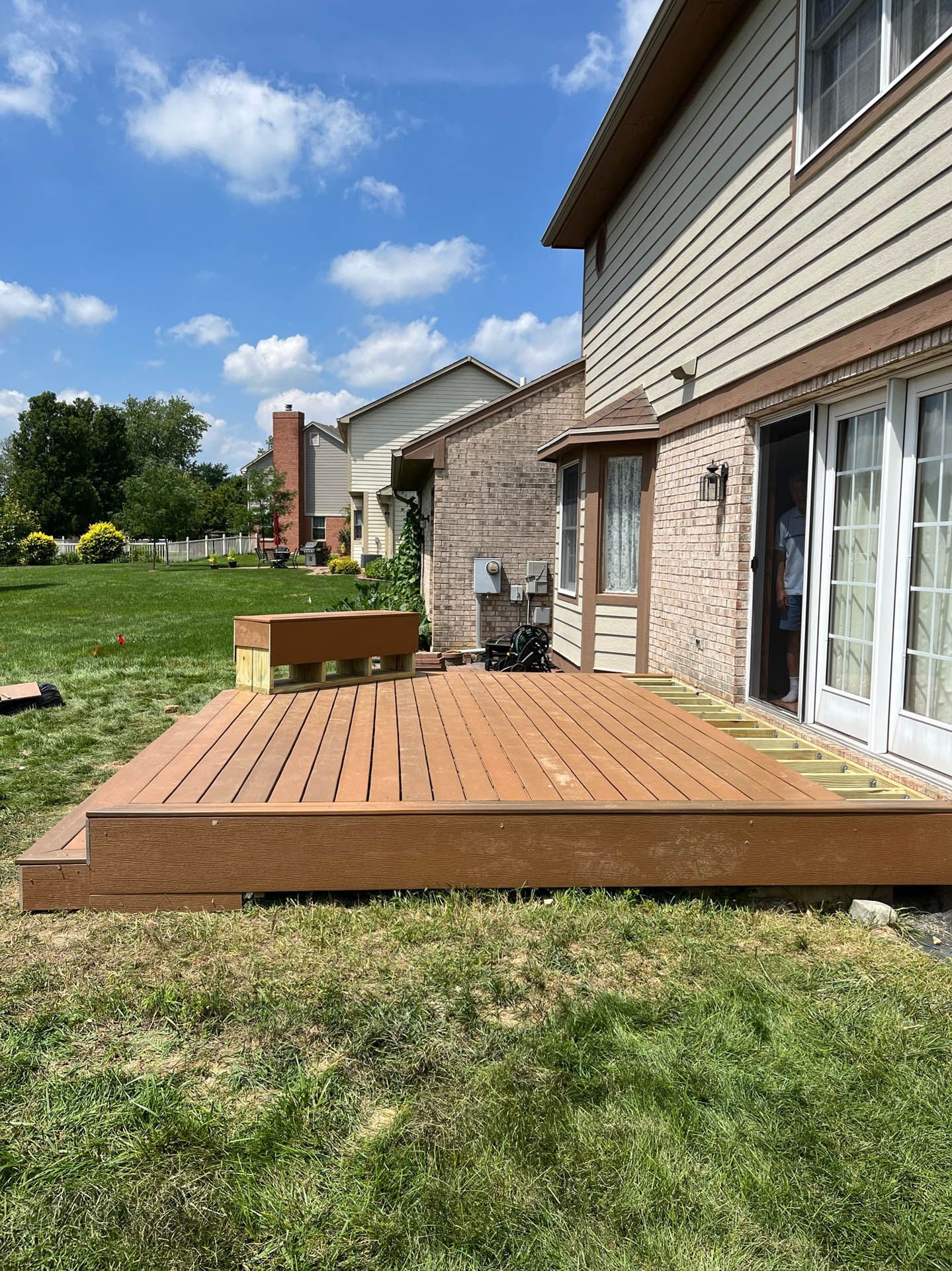 A wooden deck is sitting in the grass in front of a house.