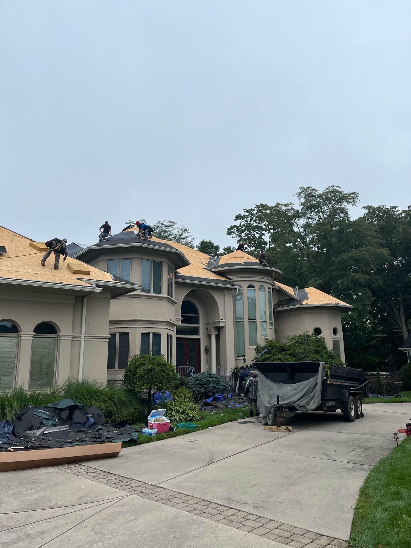 A large house is being remodeled with a truck parked in front of it.