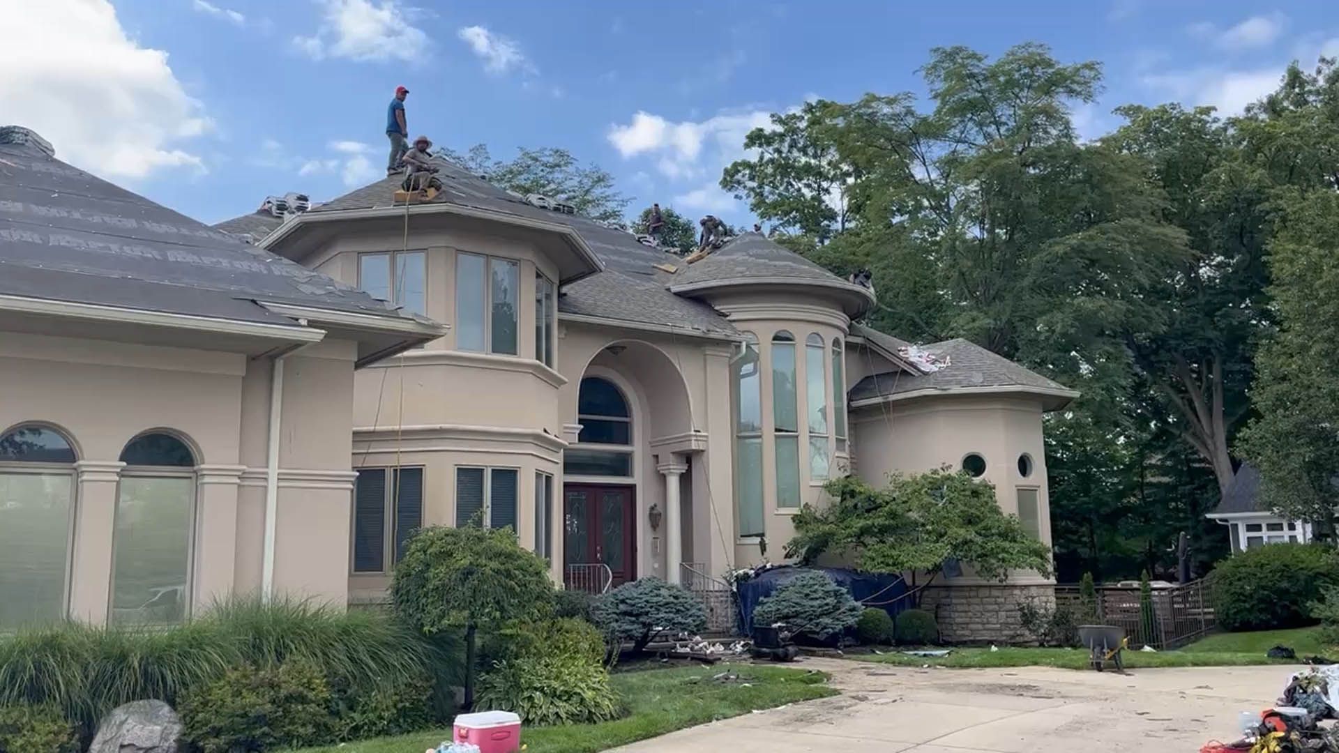 A man is standing on the roof of a large house.