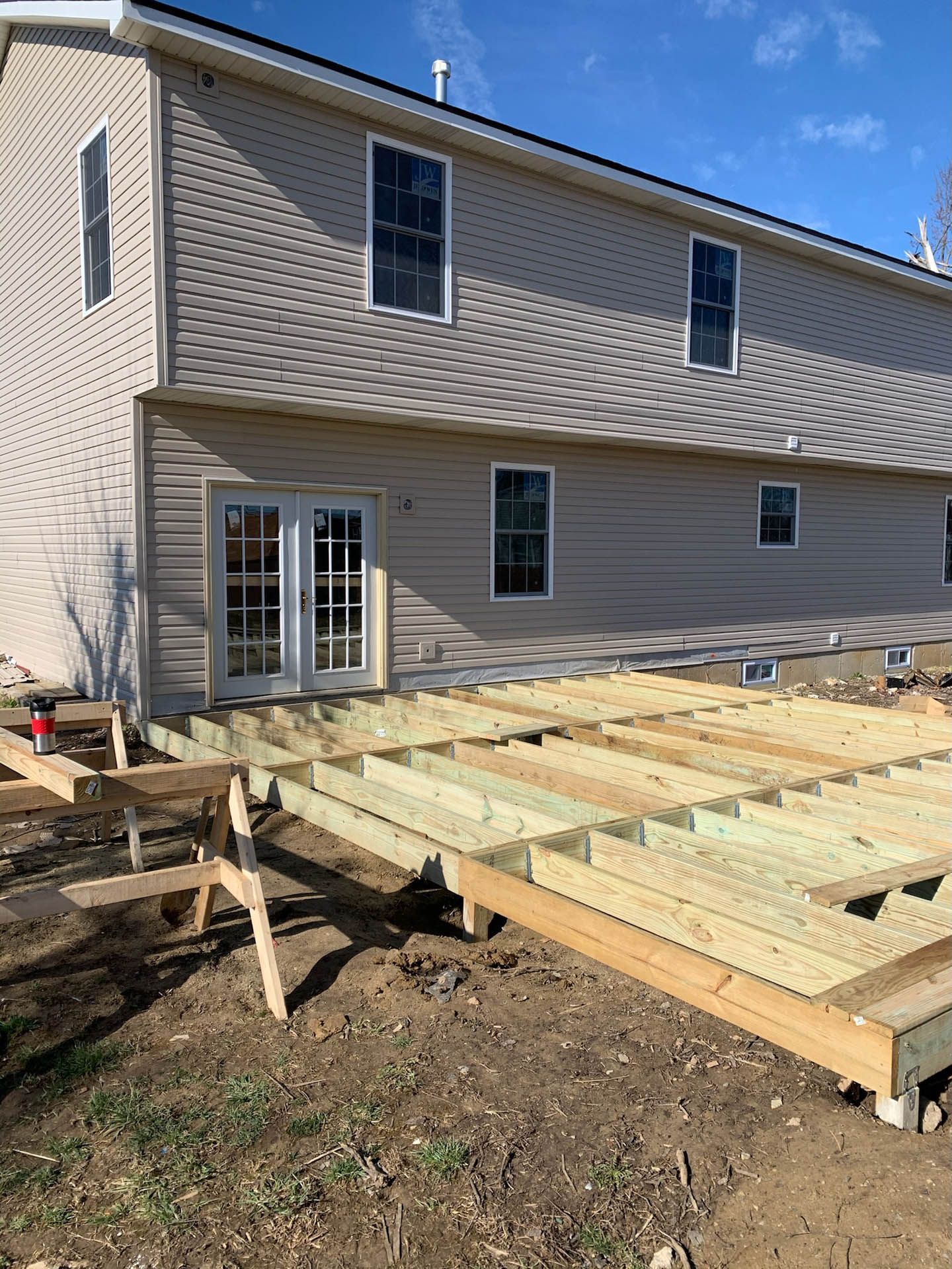A wooden deck is being built in front of a house.