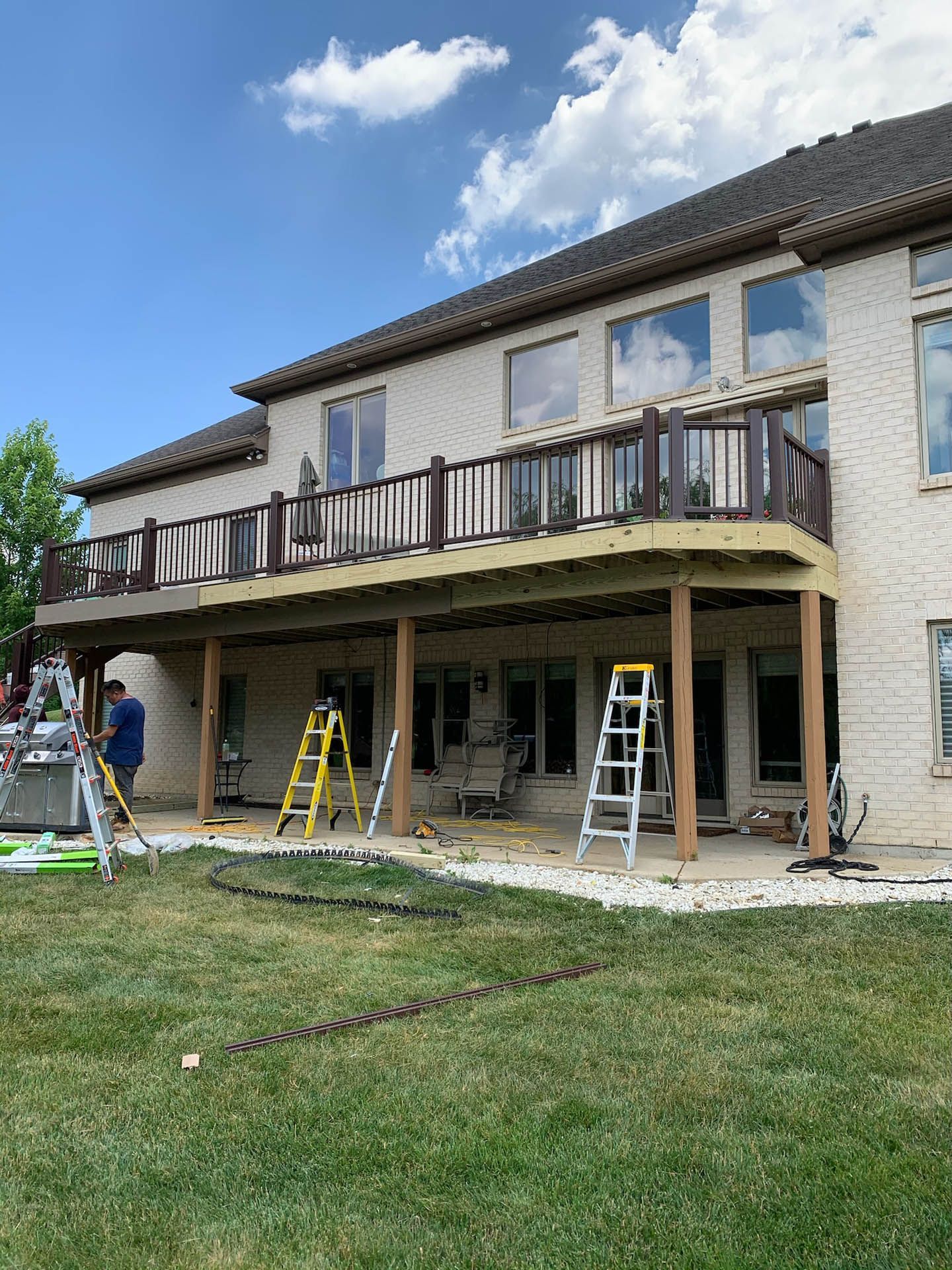 A large house with a large deck and a ladder in front of it.